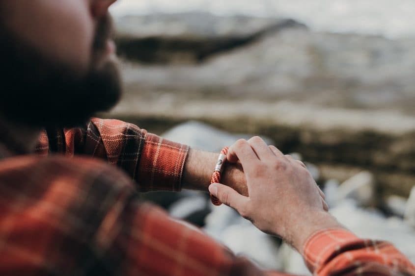 Man wearing orange climbing rope bracelet on rocks