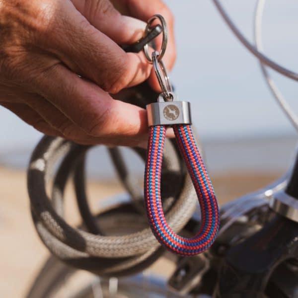 Person holding red and blue striped steel key fob key ring